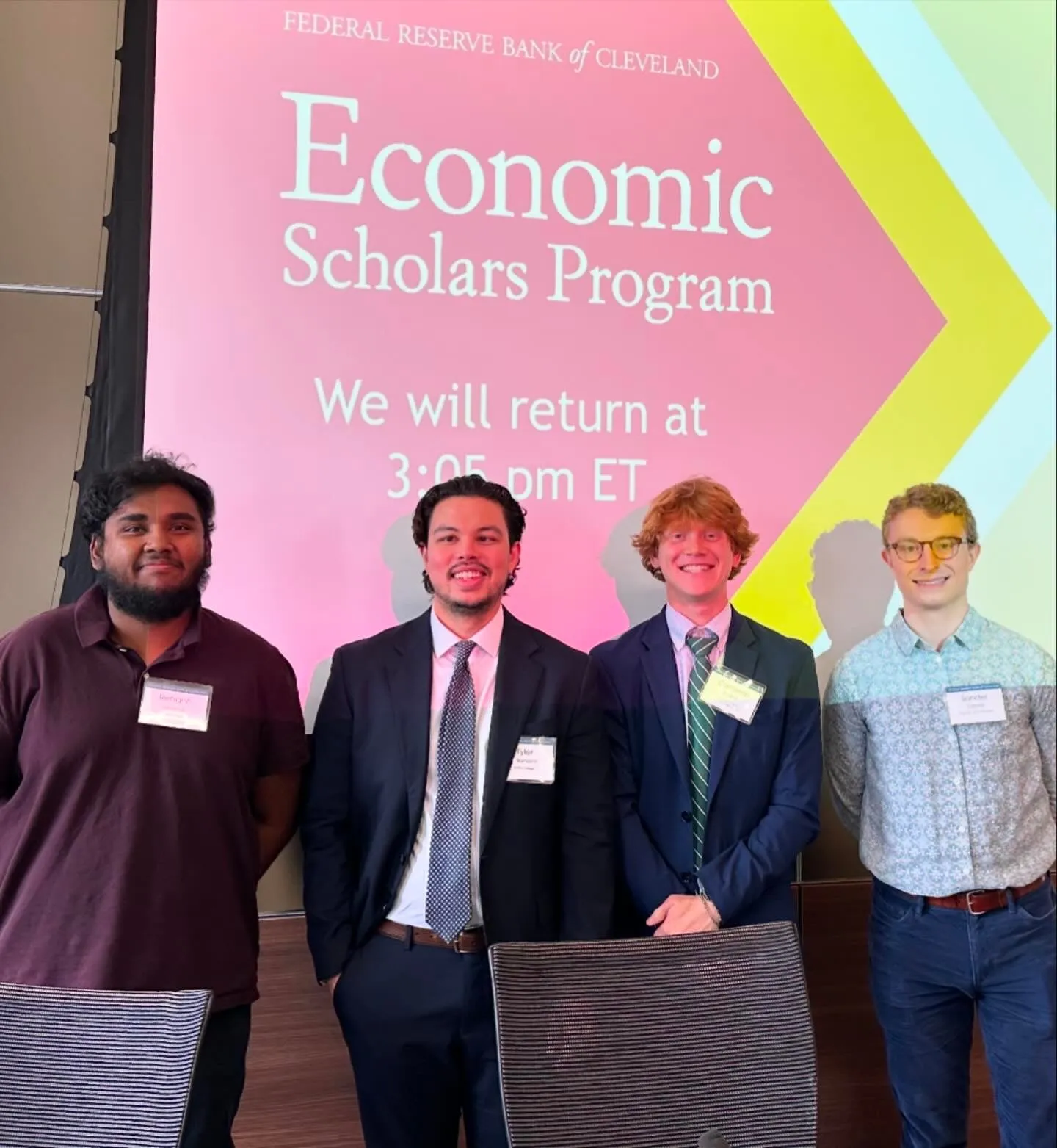 Tyler Sotomayor with three fellow participants in front of the Economic Scholars Program screen at the Federal Reserve Bank of Cleveland