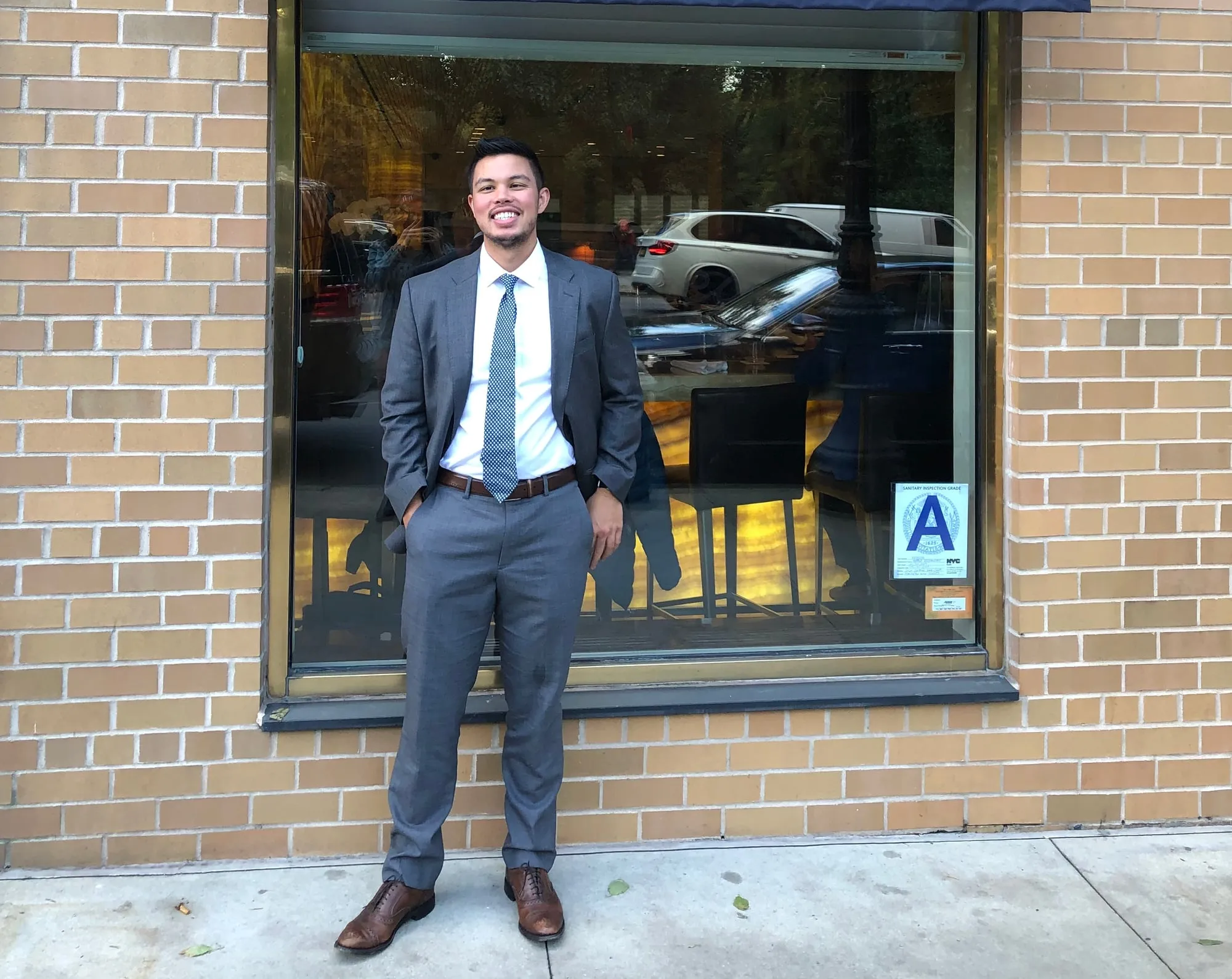 Tyler Sotomayor in a grey suit on a New York City sidewalk
